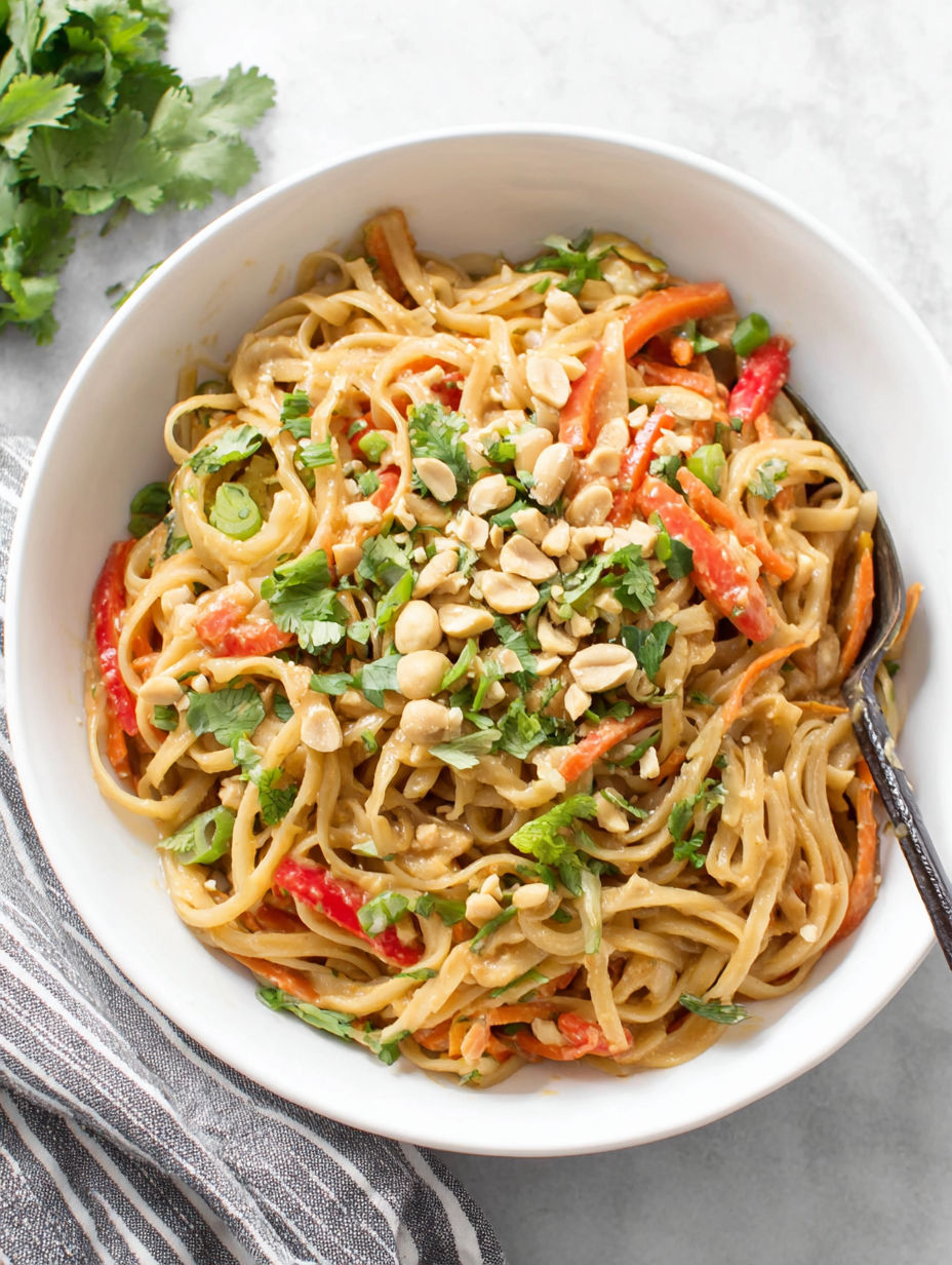 A bowl of noodles with vegetables and nuts.