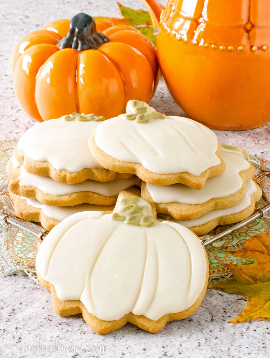 A plate of cookies with pumpkin and white icing.