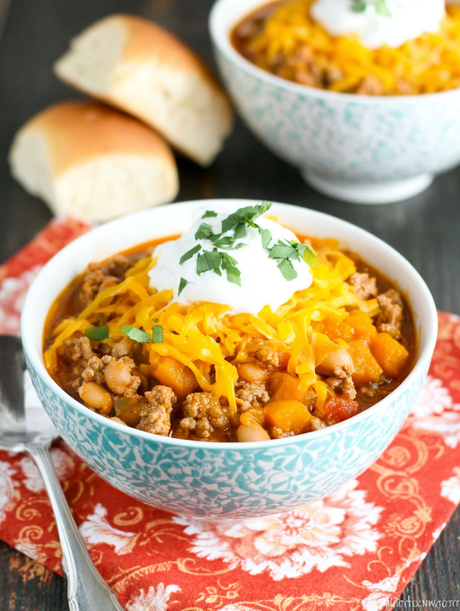 A bowl of chili with a dollop of sour cream on top.