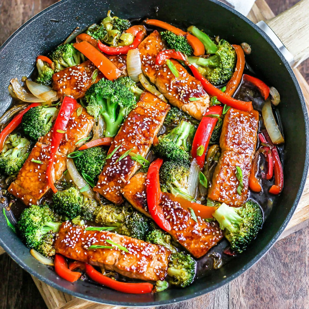 A pan of food with broccoli and red peppers.