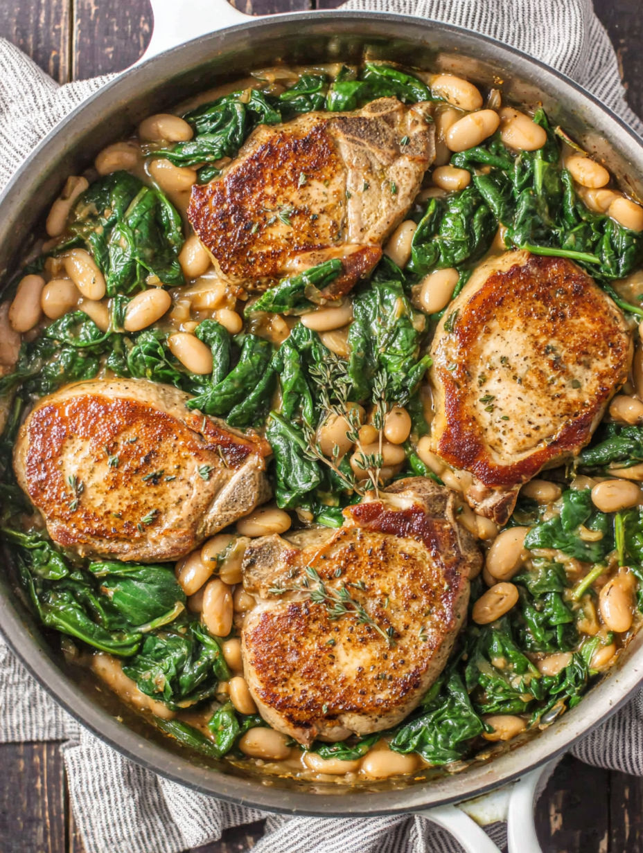 A skillet dinner with pork chops, white beans, and spinach.