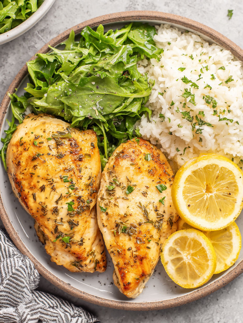 A plate of food with chicken, rice, and lemon wedges.