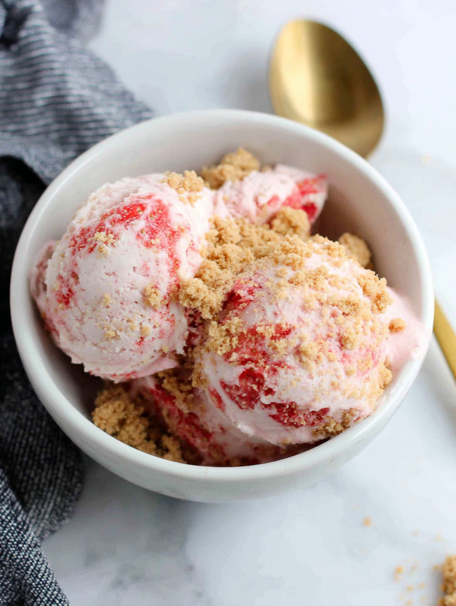 A bowl of red and white ice cream with crumbles.