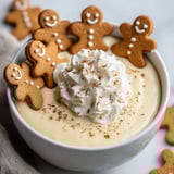 A bowl of eggnog pudding dip with gingerbread cookies on top.