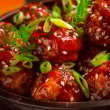 A bowl of meatballs covered in a sticky honey garlic sauce.