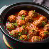 A pot of meatballs cooking in a tomato sauce.