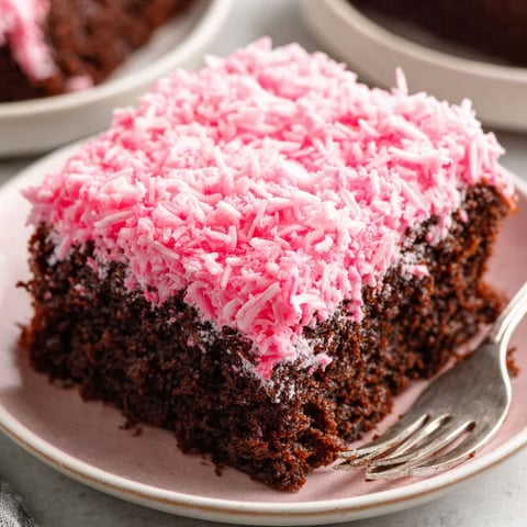 A slice of chocolate cake with pink frosting.