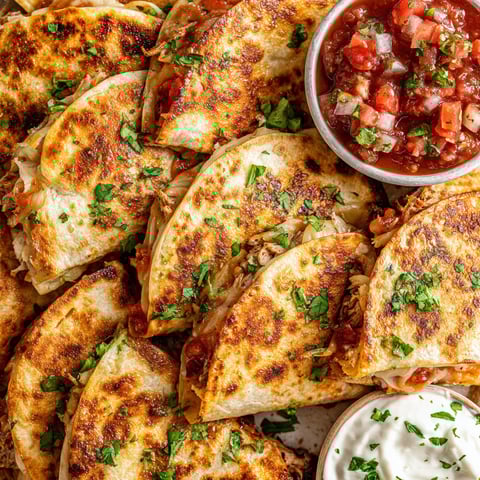 Mini chicken quesadillas with tomatoes and sour cream.