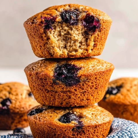 Three stacked muffins with blueberries on top.