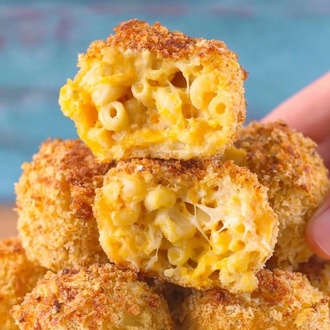 A hand holding a crispy baked mac and cheese bite.