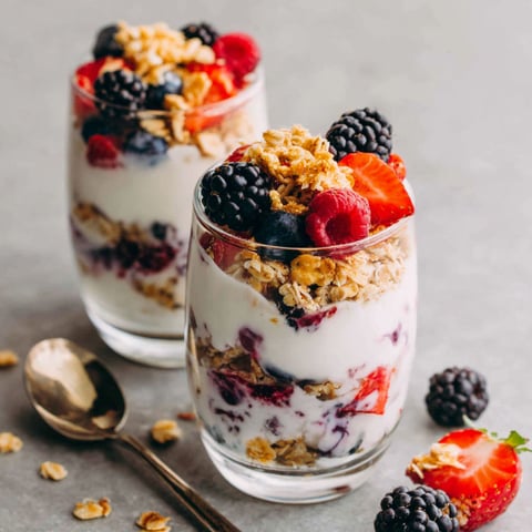 Two glasses of yogurt parfait with berries and granola.