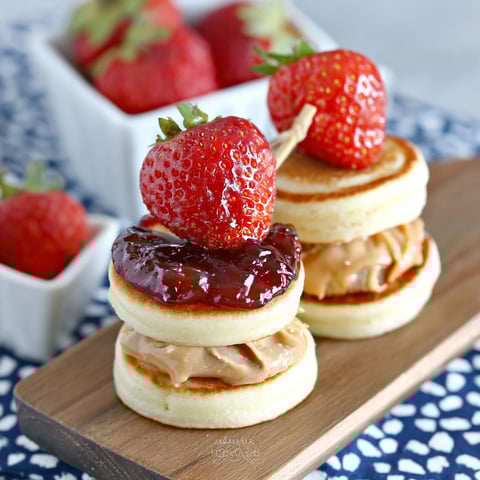 Two mini pancakes stacked with peanut butter and jelly.