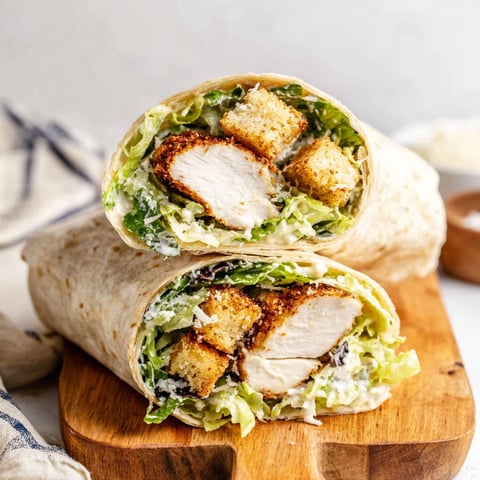 A chicken Caesar wrap is shown on a cutting board.
