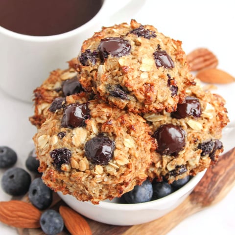 A bowl of oatmeal cookies with chocolate chips and blueberries.