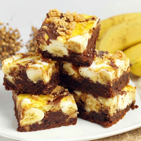 A plate of brownies with bananas on top.
