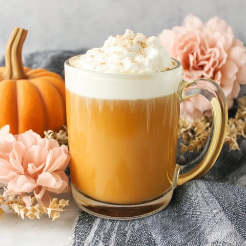 A glass of pumpkin spice milk with whipped cream.
