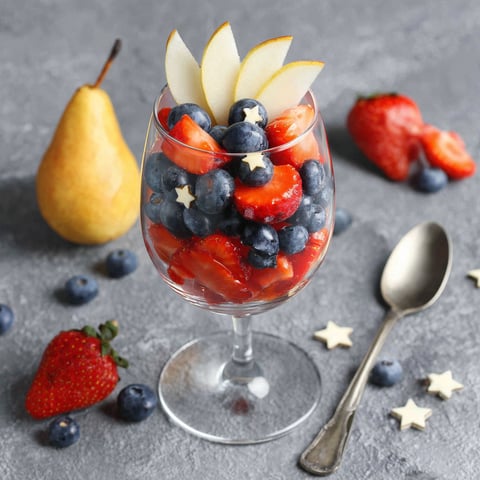 A glass of red white and blue fruit salad.