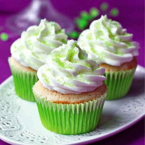 Two green cupcakes with white frosting.
