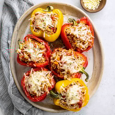 A plate of stuffed peppers with cheese and ground chicken.