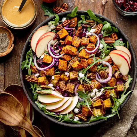 A bowl of salad with roasted sweet potatoes.