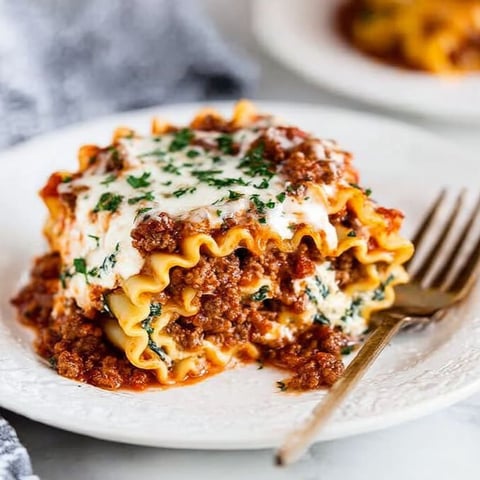 A plate of lasagna roll-ups with cheese and sauce.