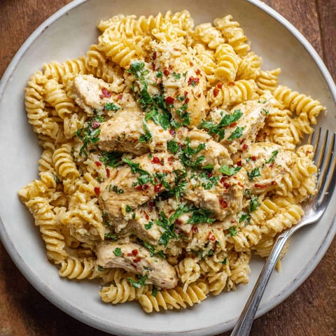 A plate of pasta with chicken and parmesan cheese.