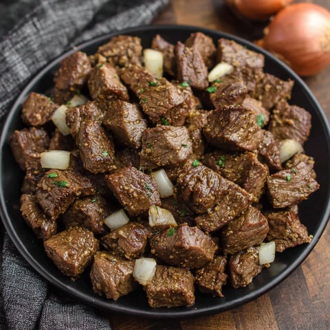 A plate of beef with onions and peppers.