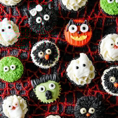 Halloween cupcakes with various designs and colors.