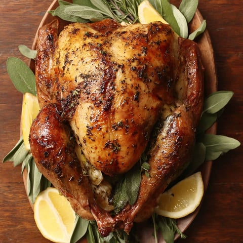 A roasted turkey with lemon wedges on top.