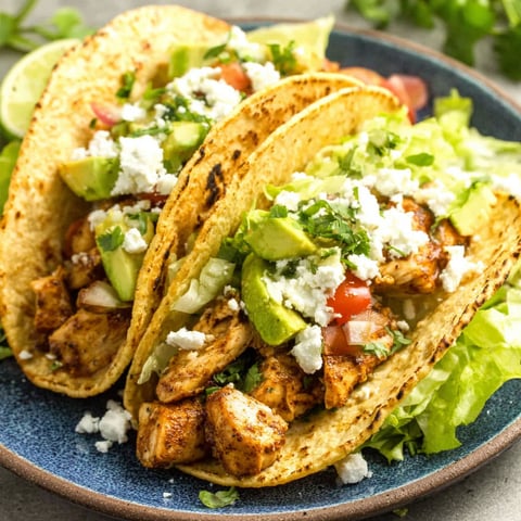 Two chicken tacos with lettuce and avocado.