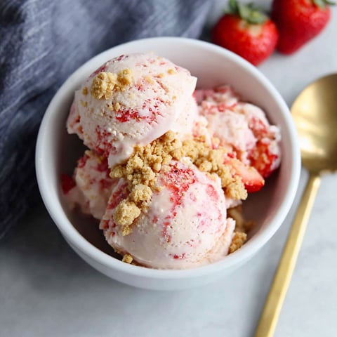 A bowl of ice cream with strawberries on top.