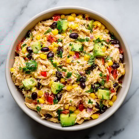 A bowl of chicken salad with corn, tomatoes, and black beans.