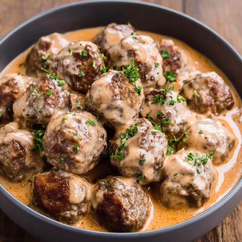 A bowl of meatballs in a creamy sauce.