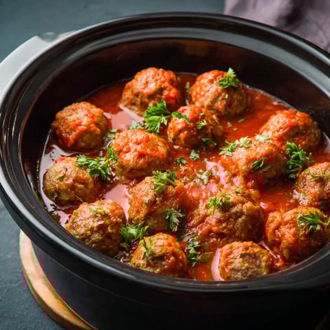 A pot of meatballs cooking in a tomato sauce.